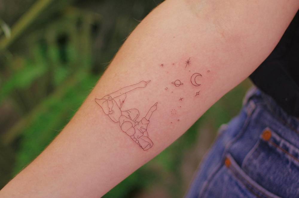 Stargazing tattoo in fine line style located on the inner forearm.