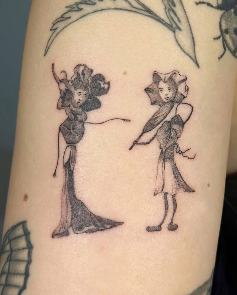 Anthropomorphised flowers tattooed on the upper arm.