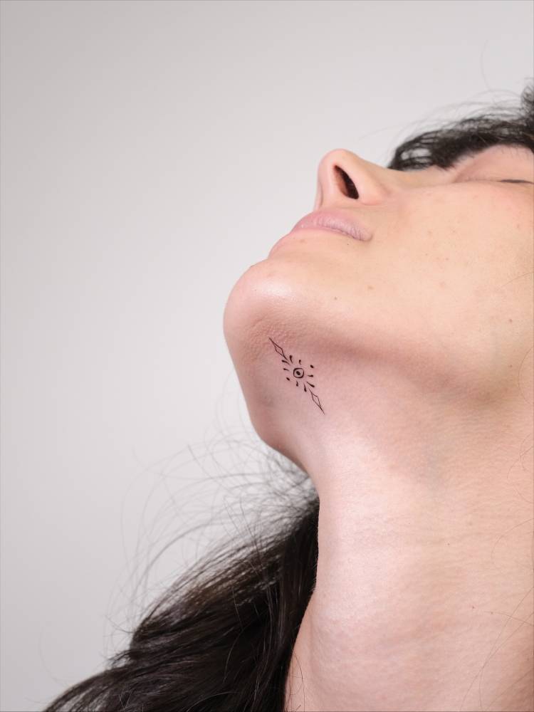 Minimalistic ornamental eye tattoo located on the face.