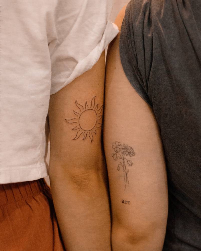 Fine line sun and tiny word "art" tattoos.