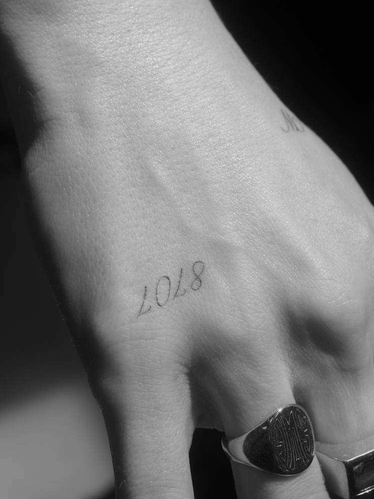 Number "8707" tattoo placed on the hand.