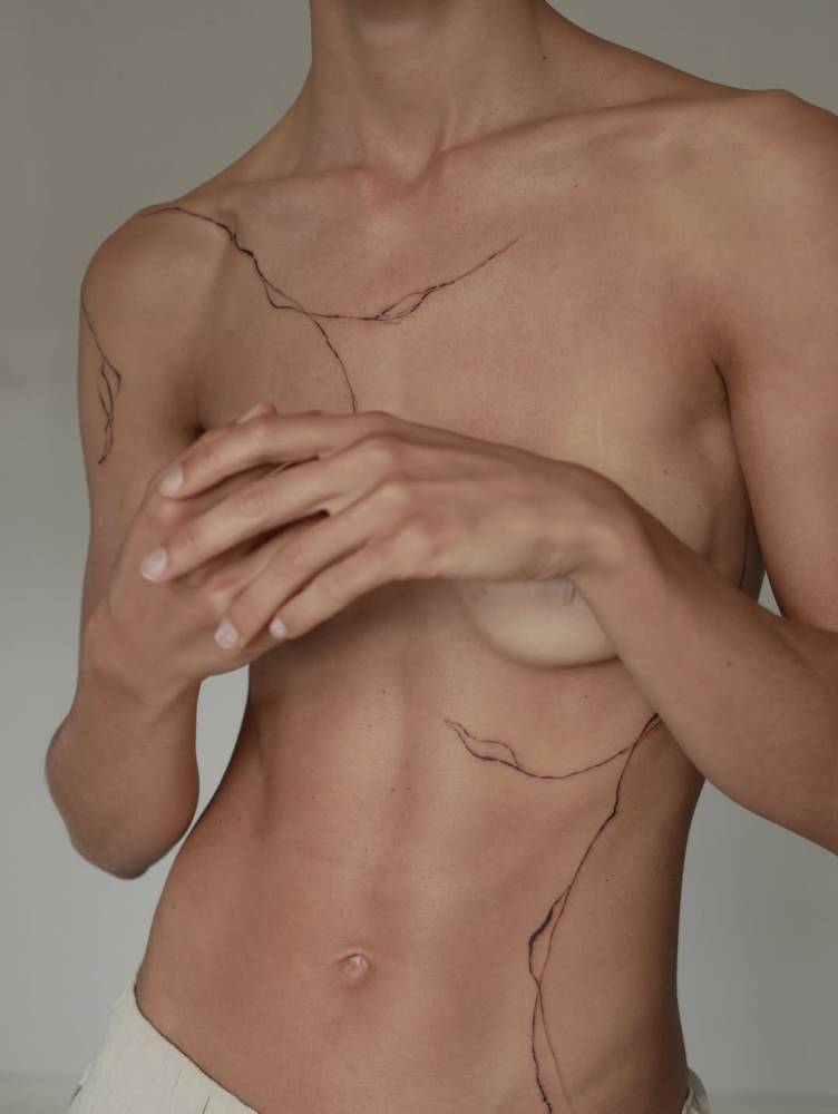 Leaves tattooed on the shoulder and ribs, illustrative style.