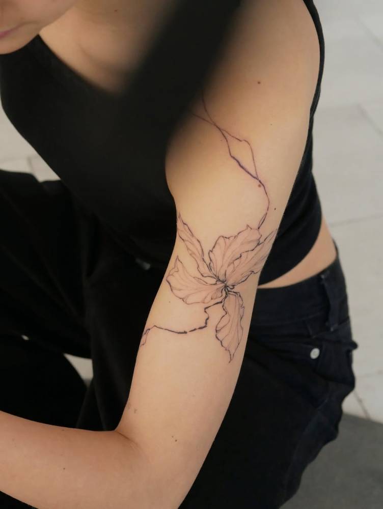 Iris flower tattoo located on the upper arm, illustrative style.