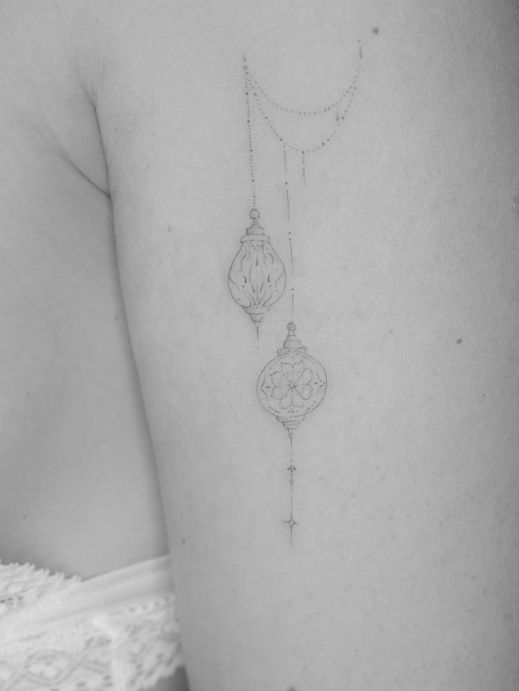 Ornamental lanterns tattoo in fine line style, placed on the upper arm.