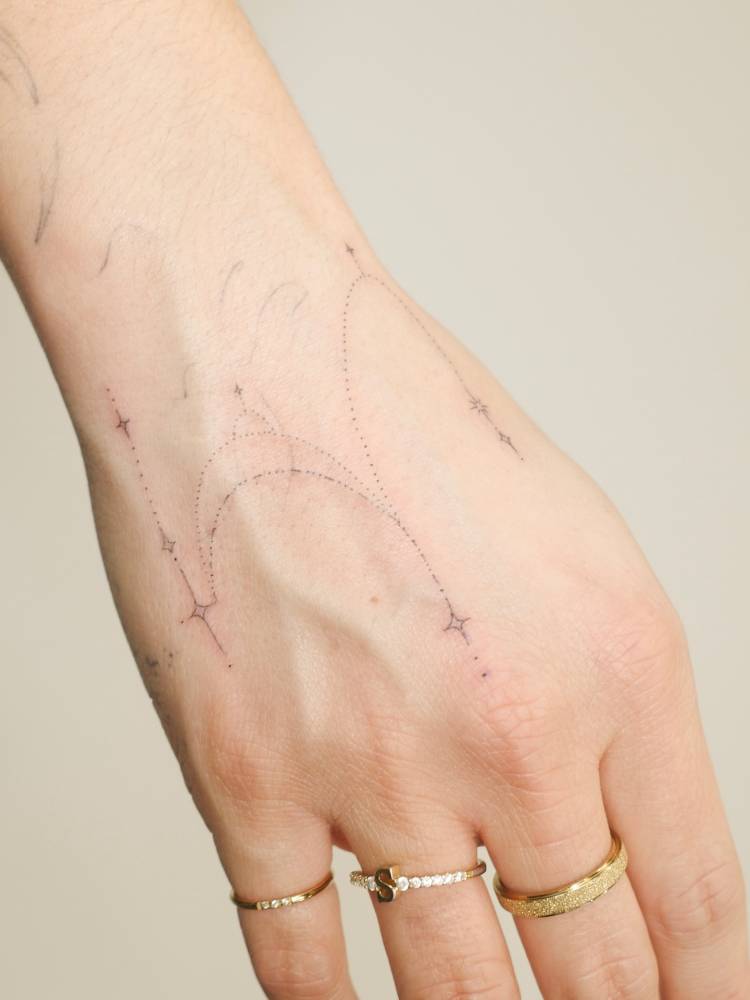 Ornamental design tattooed on the hand, fine line style.