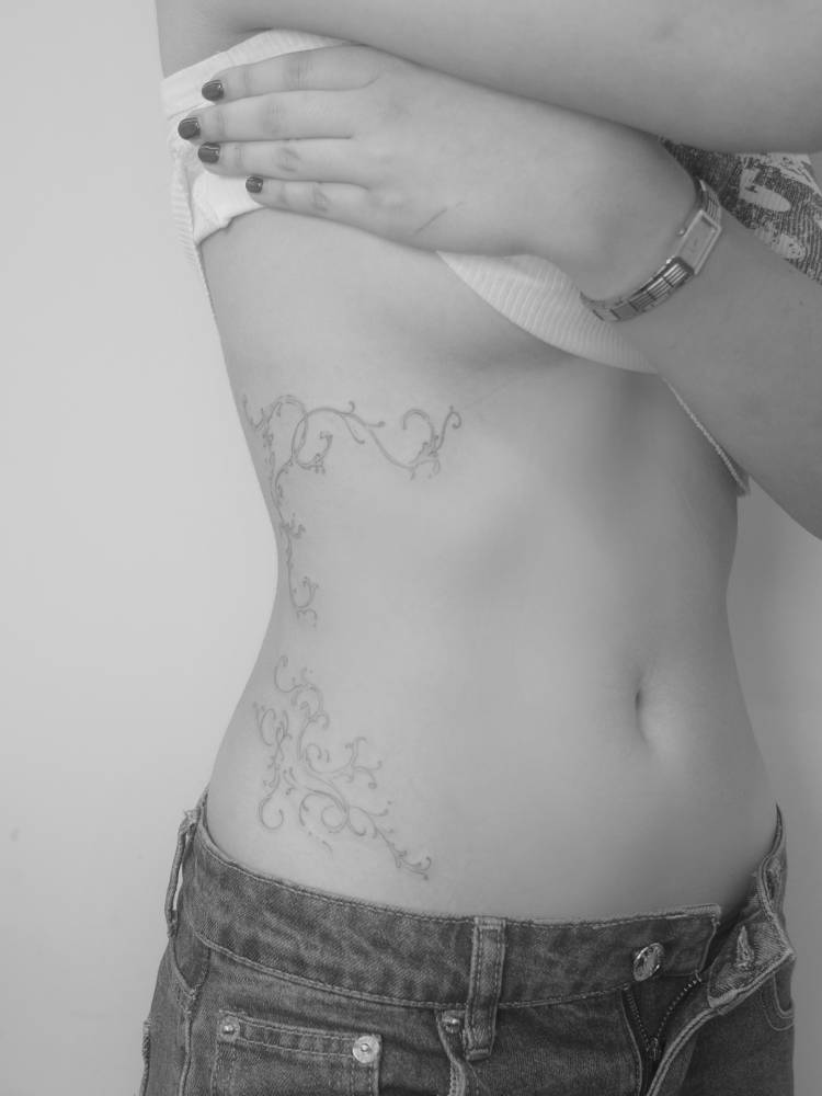 Vines tattoo in fine line style located on the waist