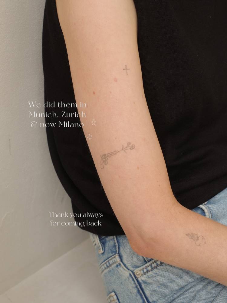 Fine line style revolver and flowers tattoo located on the upper arm.