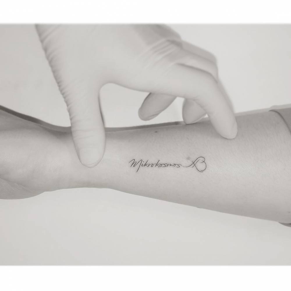 "Mikrokosmos" lettering tattoo located on the wrist.