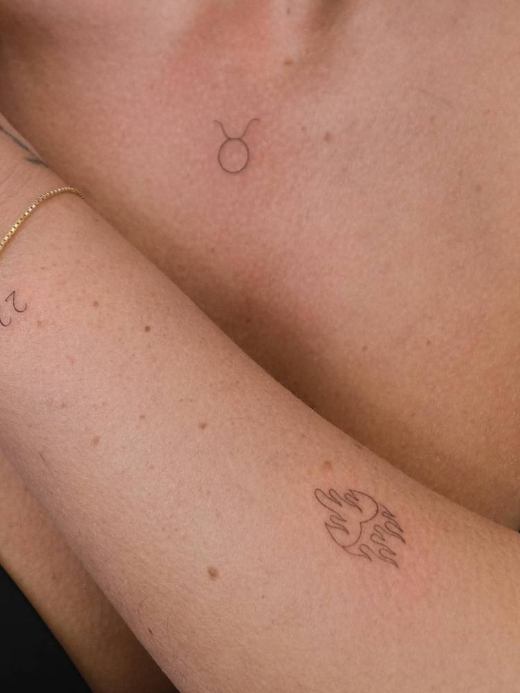 Fine line style flaming heart tattoo located on the forearm.