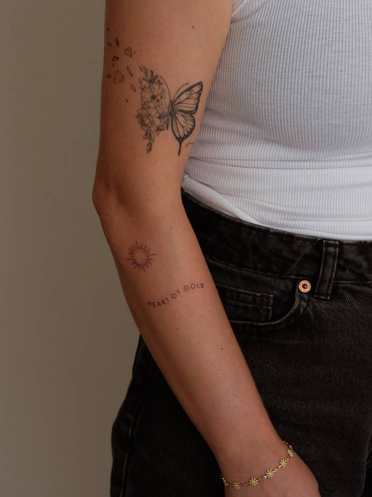 "Heart of gold" and sun tattoo located on the forearm.
