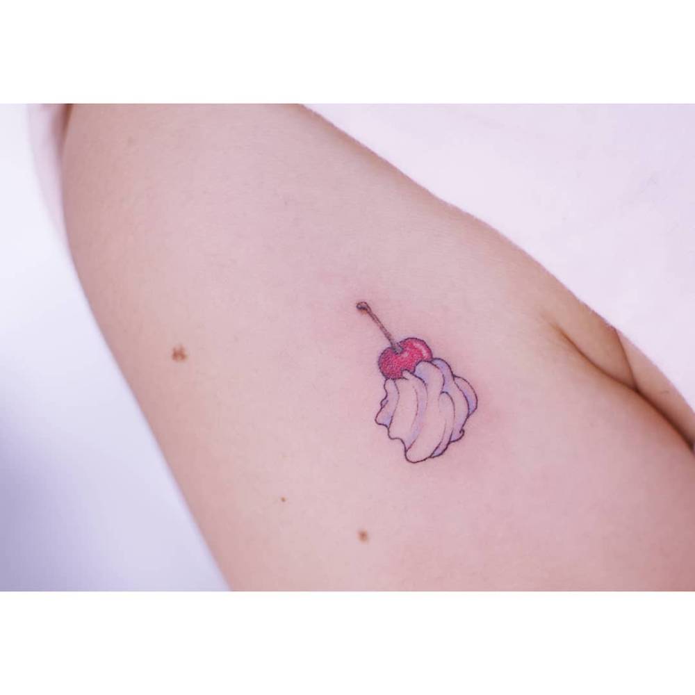 Cherry and whipped cream tattoo in illustrative style.