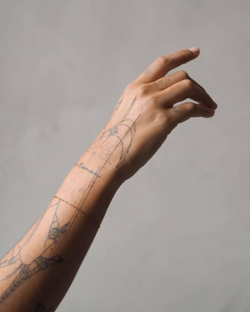 Fine line style ornamental design tattooed on the hand and wrist.