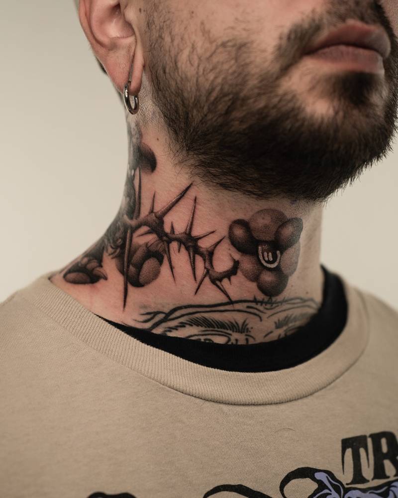Thorns and flower tattoo located on the neck.