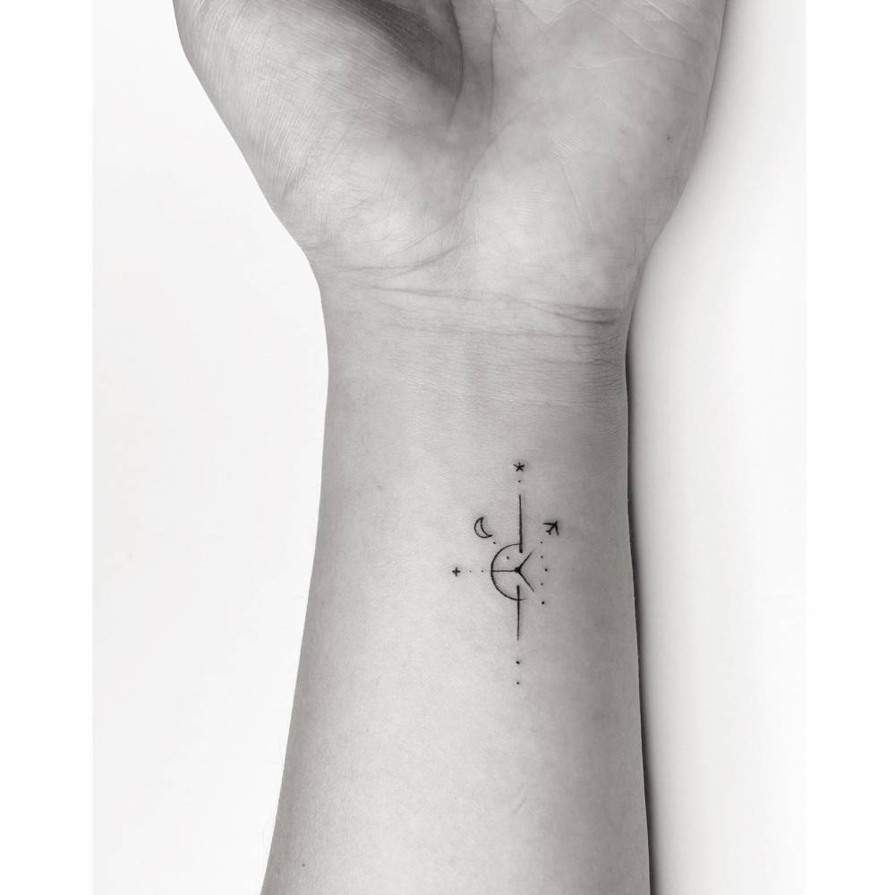 Compass rose tattoo located on the wrist, minimalist style.