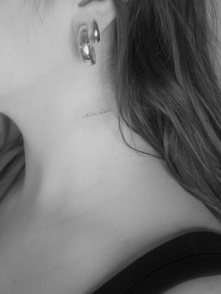 Handwritten font word "sonder" tattooed on the neck.