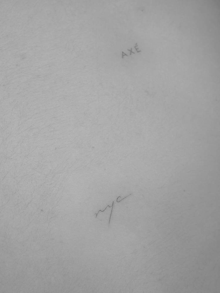 "NYC" lettering tattoo located on the back.