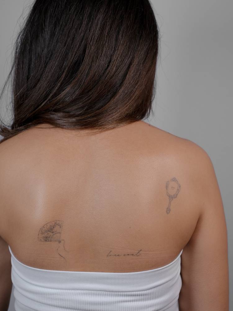 Hand fan and "free soul" tattoos located on the back.
