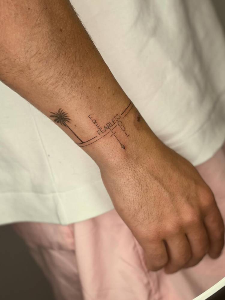 Words "free", "fearless" and soul wristband tattoo.