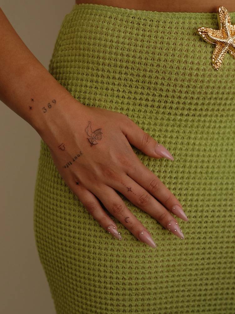 Cupid and ornaments tattooed on the hand and fingers.