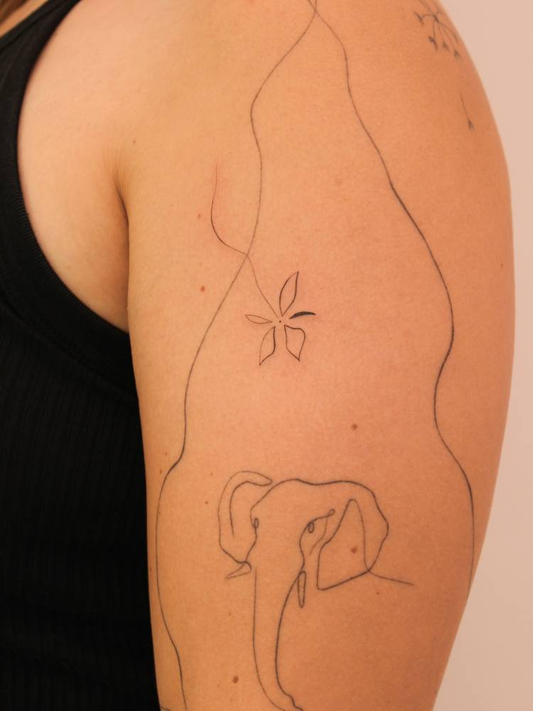 Fine line style flower tattoo located on the upper arm.