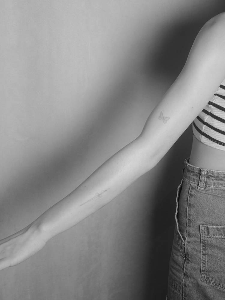 Fine line style butterfly and sword tattoos located on the arm.