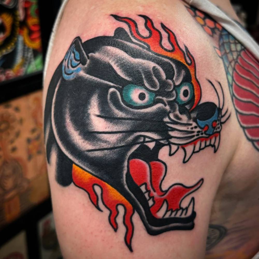 Panther head tattoo done on the shoulder, traditional style.