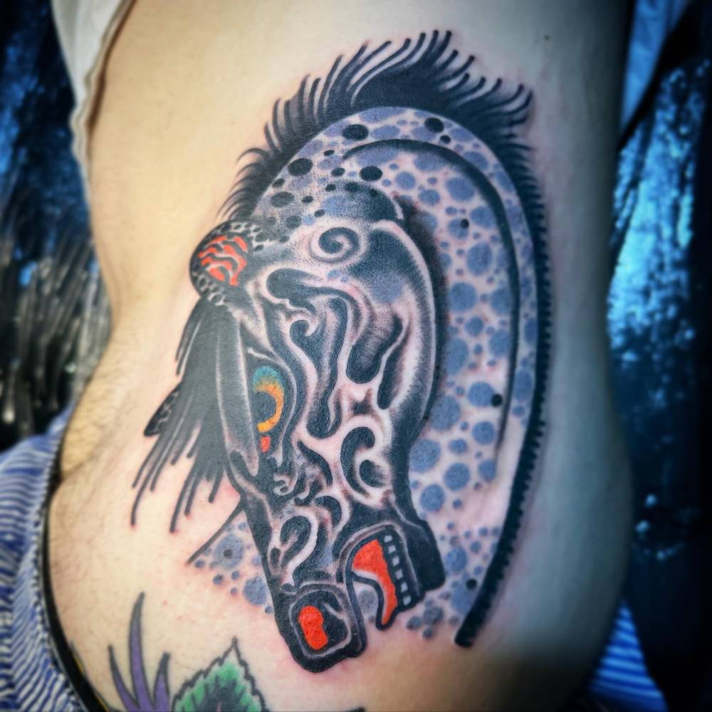 Horse head tattoo located on the waist, done in traditional style.
