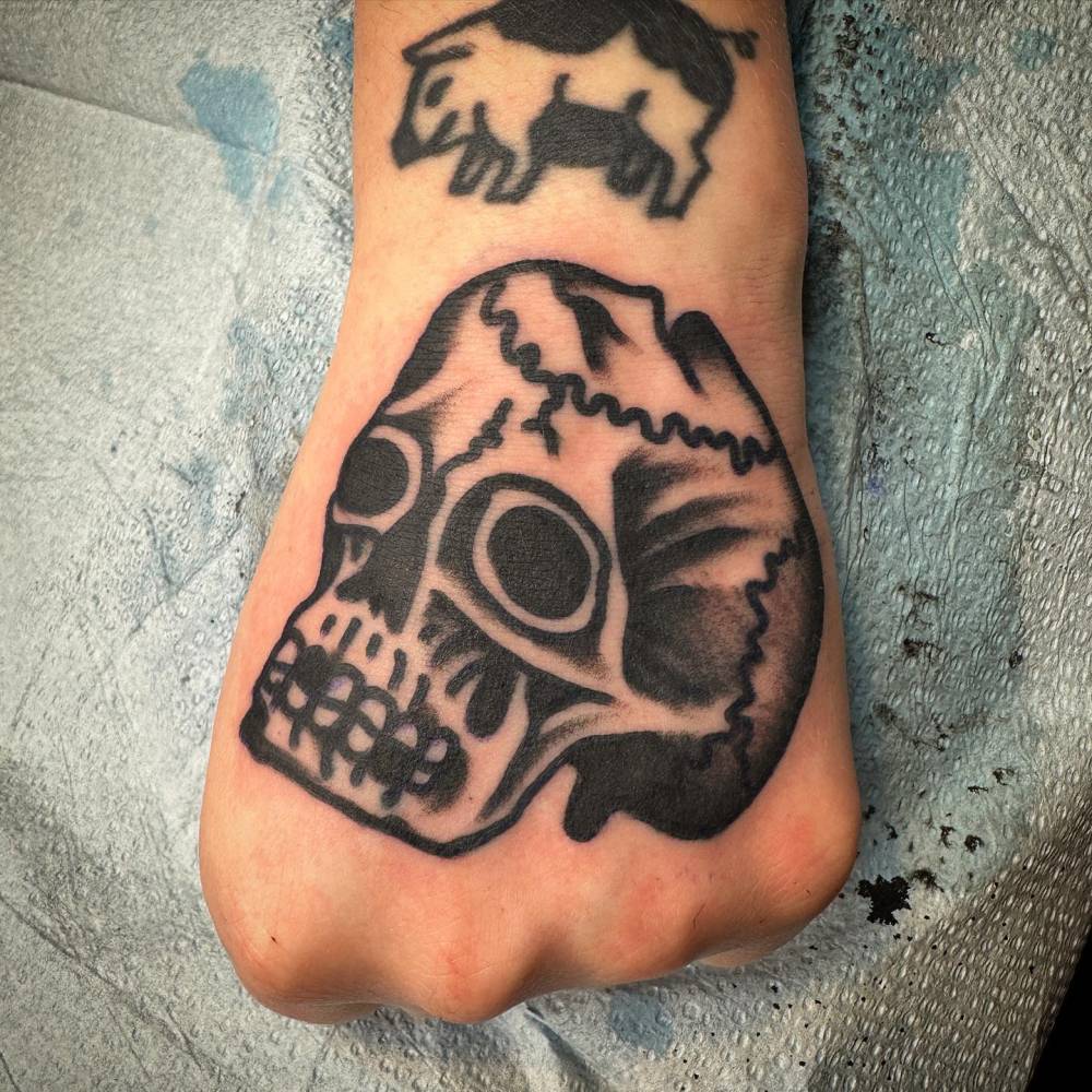 Skull in traditional style tattooed on the hand.