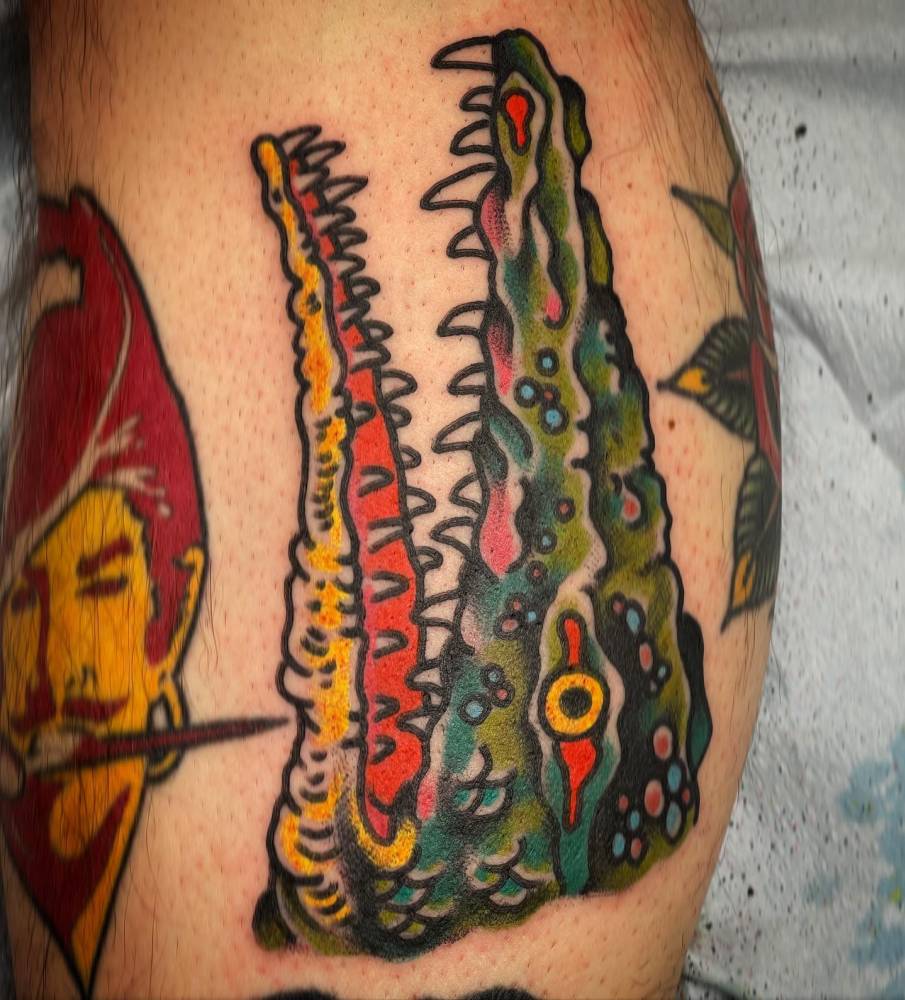 Alligator head in traditional style tattooed on the calf.