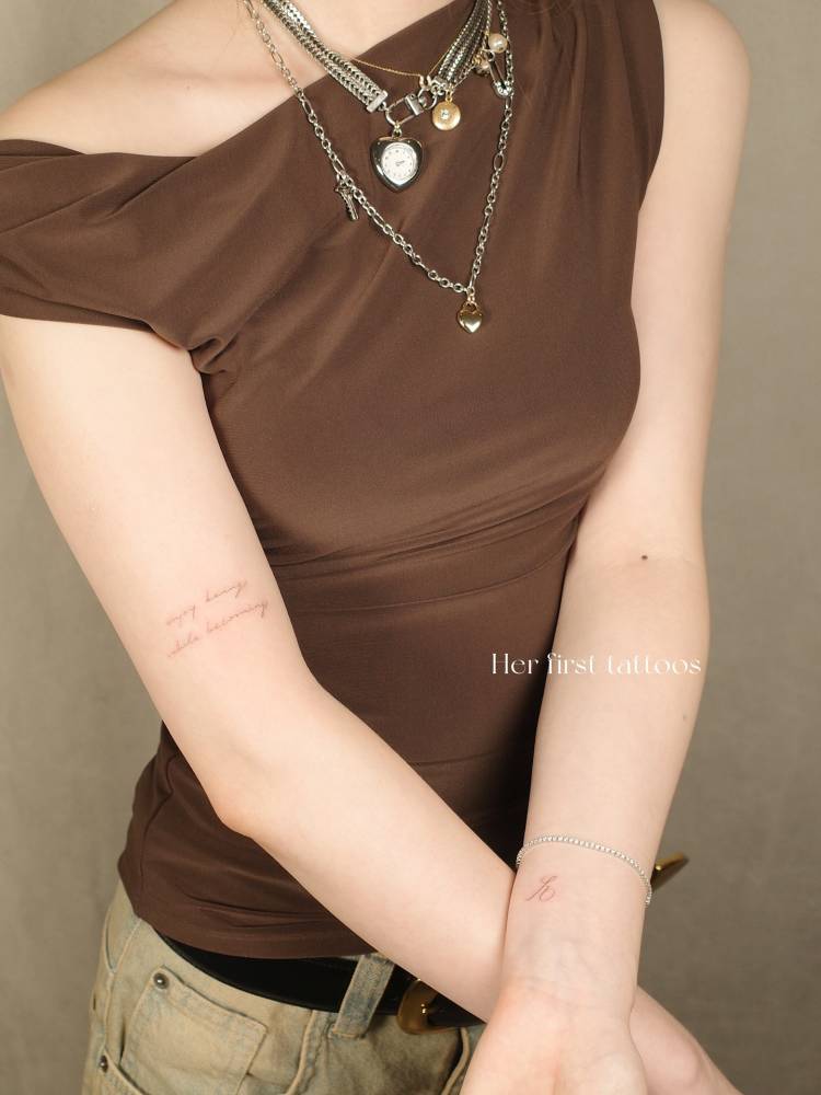 "Enjoy being while becoming" and letter "E" tattoos.
