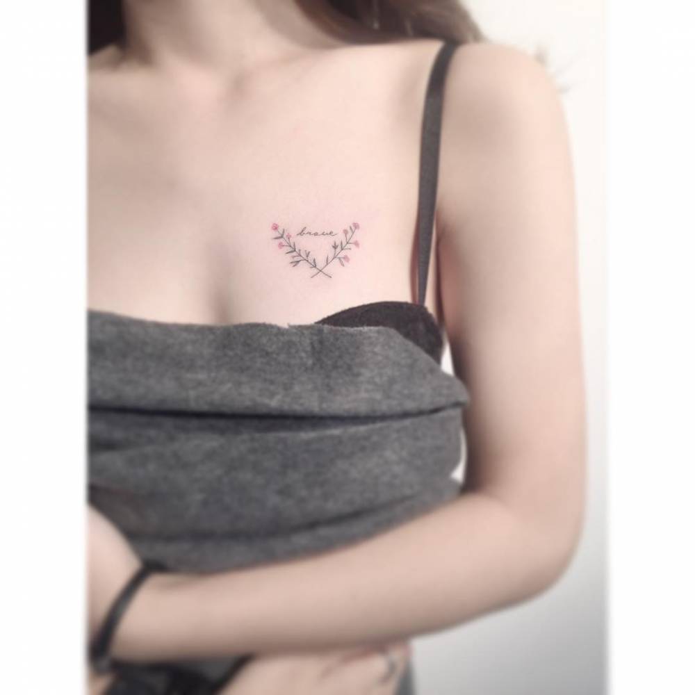 Laurel wreath and word "brave" tattoo located on the chest.
