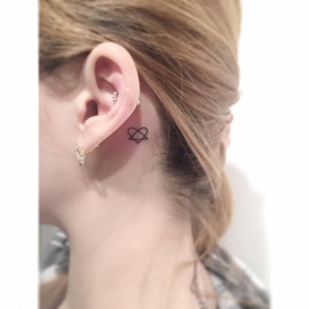 Tiny minimalist triangle and heart tattoo located behind the ear.