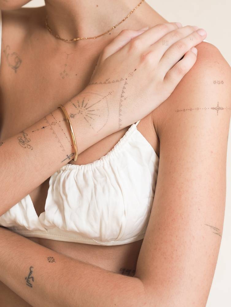 Fine line style ornamental tattoos located on the hand and upper arm.