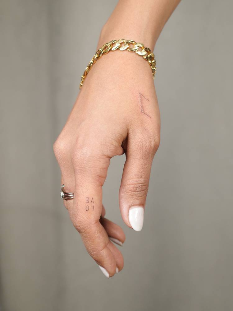 Tiny words "love" and "pray" tattooed on the hand.