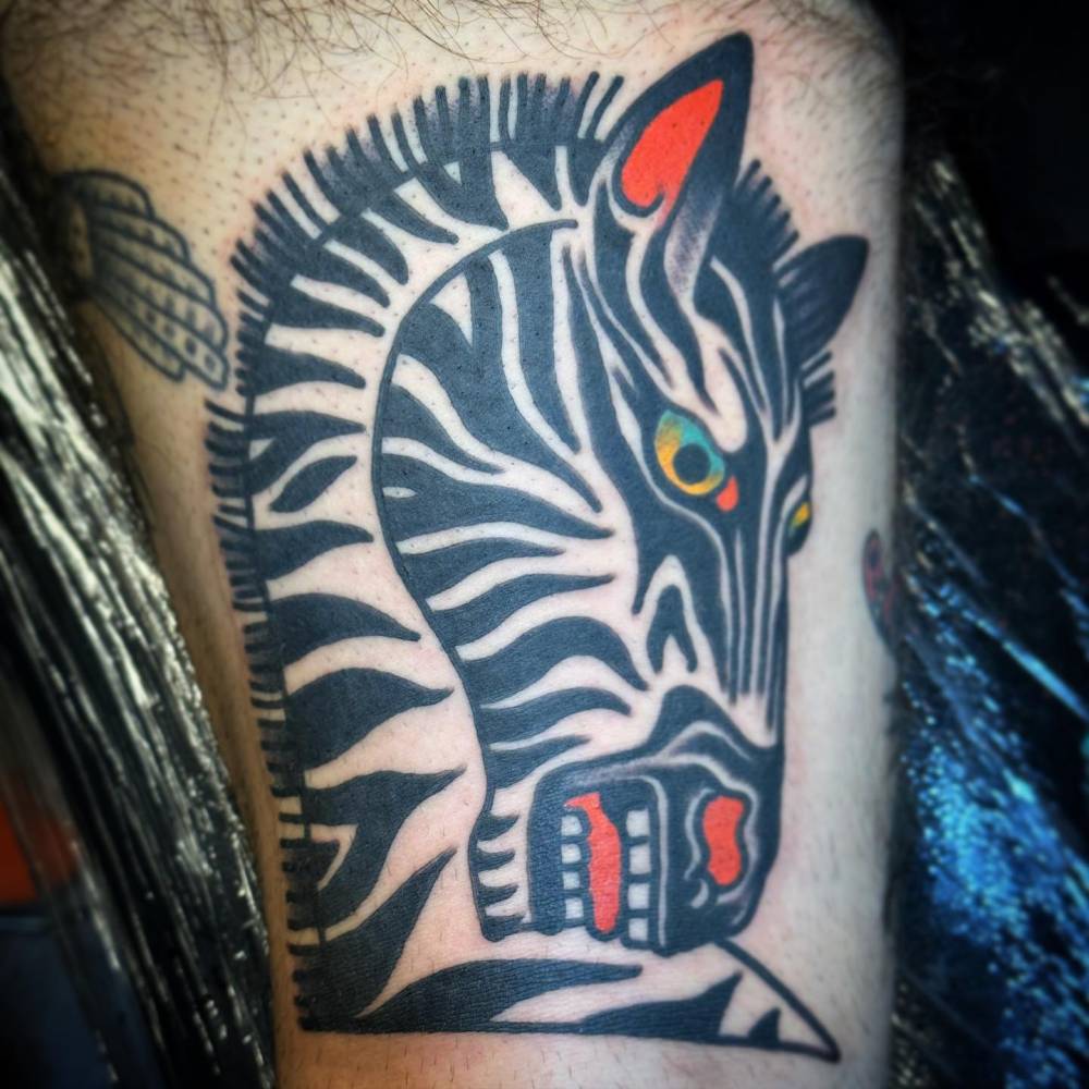 Zebra head tattoo located on the thigh, traditional style.