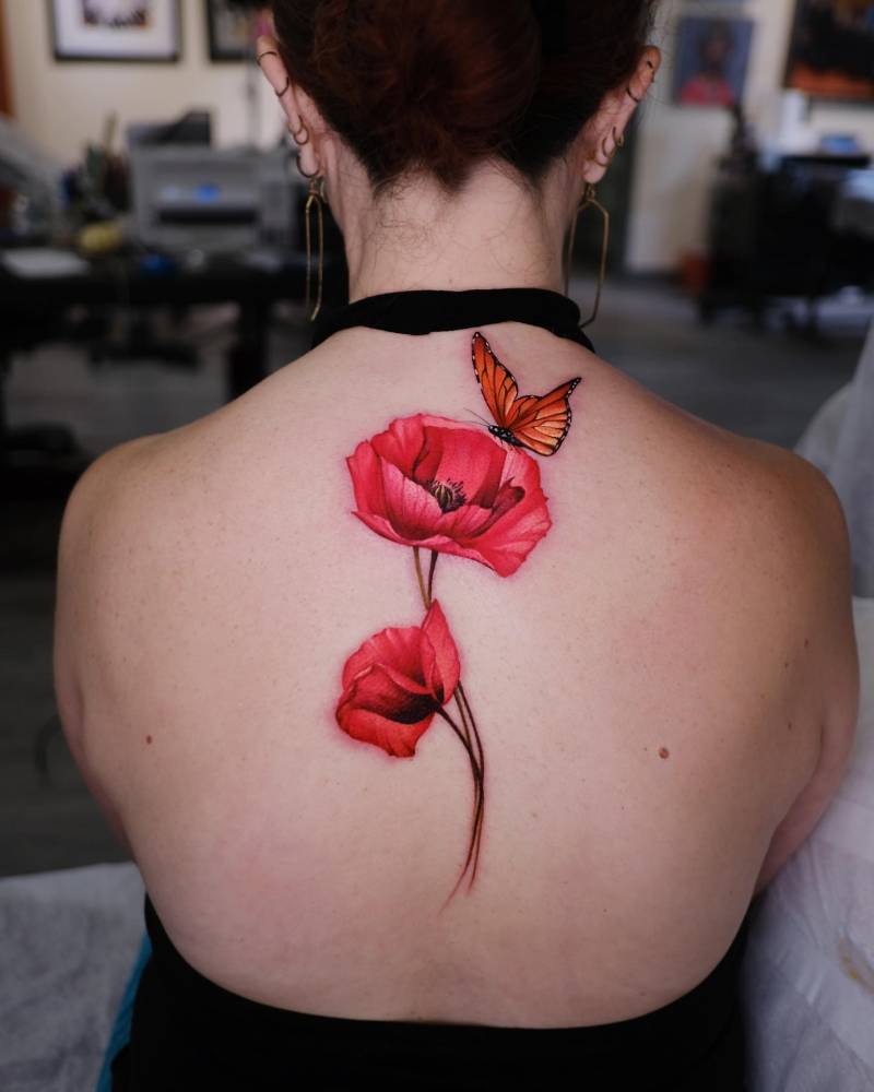 Poppy flowers and orange butterfly tattoo located on the upper back.
