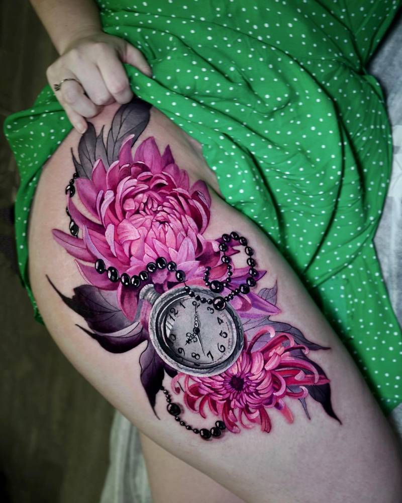 Chrysanthemum and pocket watch tattoo located on the thigh.