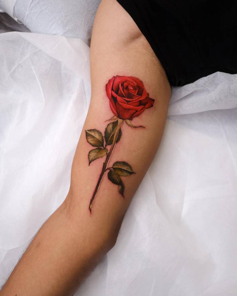 Realistic style red rose tattoo located on the inner arm.
