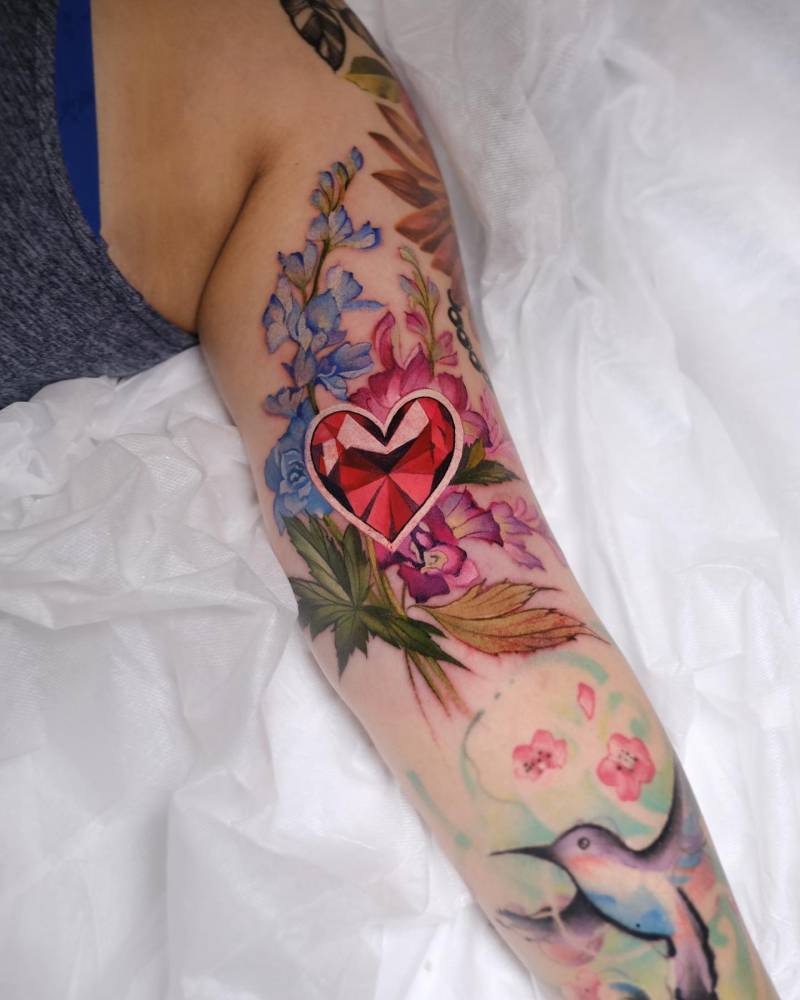 Ruby heart and flowers tattoo located on the tricep.