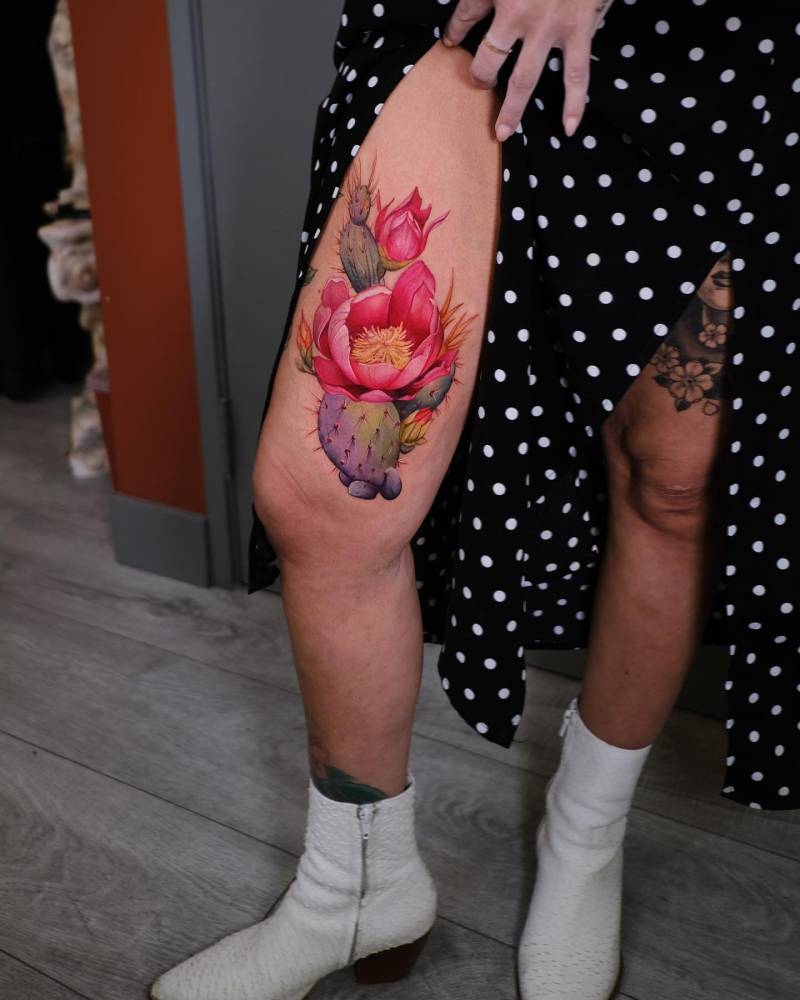 Cactus and flowers tattooed on the thigh, realistic style.