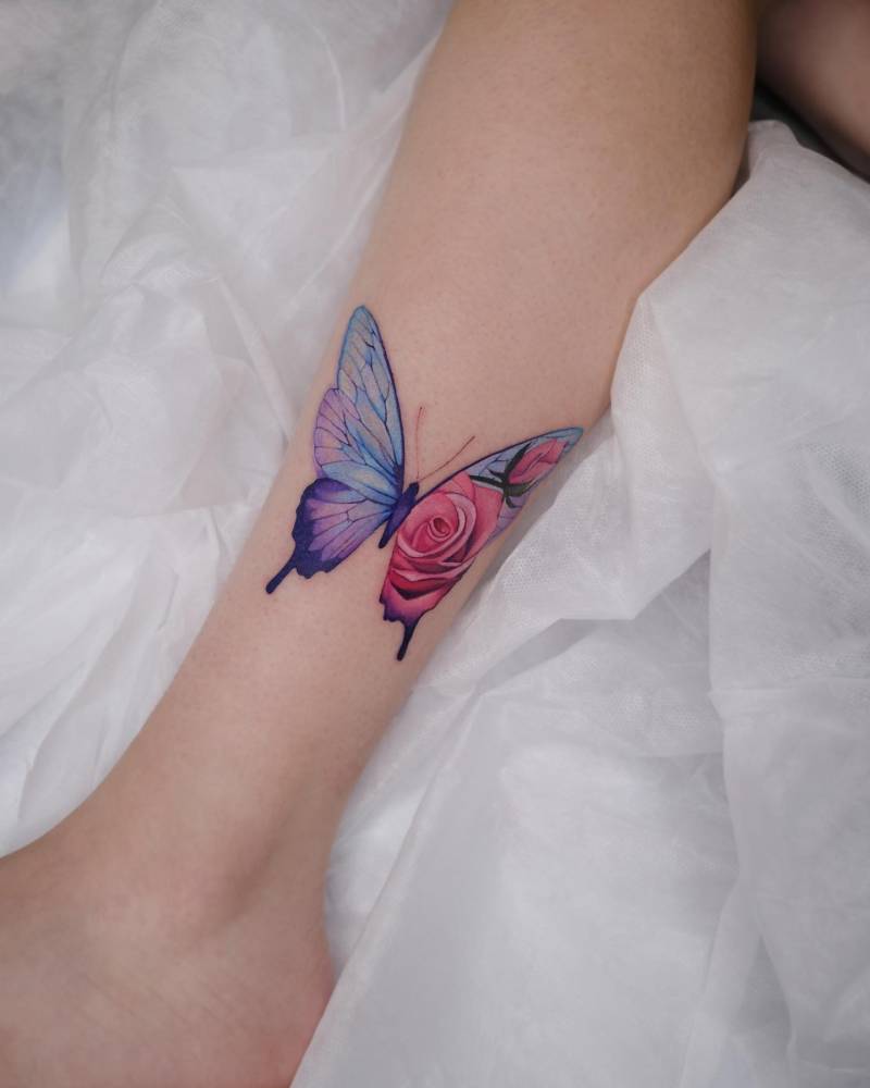 Flower butterfly tattoo located on the shin, watercolor style.