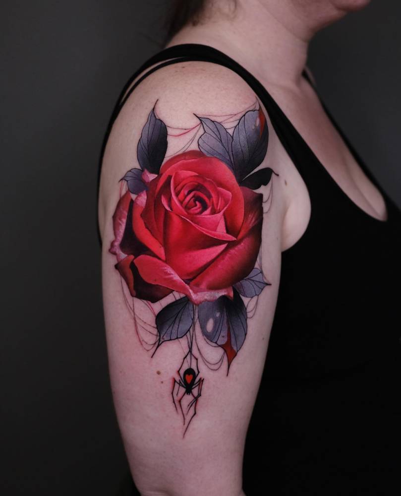 Red rose and spider tattoo located on the upper arm.