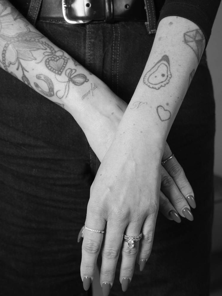 "Amor fati" and letter "N" tattoos located on the wrists.