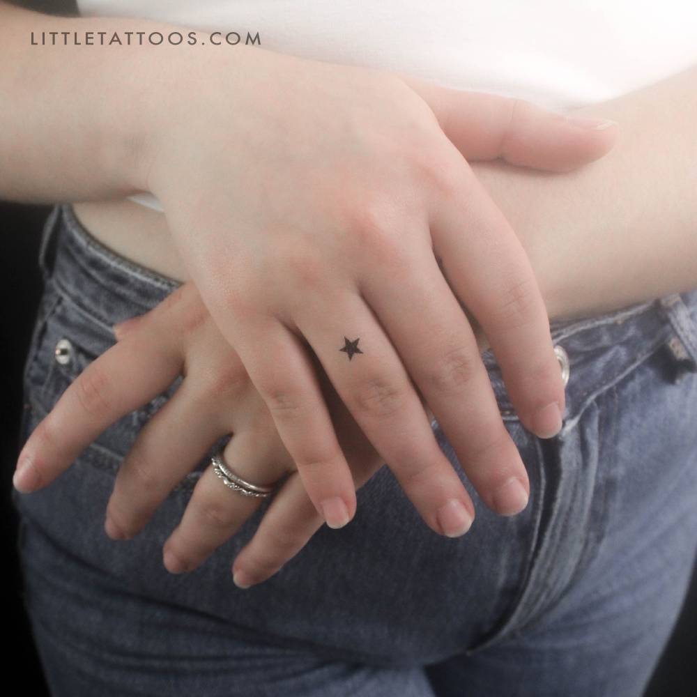 Minimalist black star temporary tattoo located on the finger.