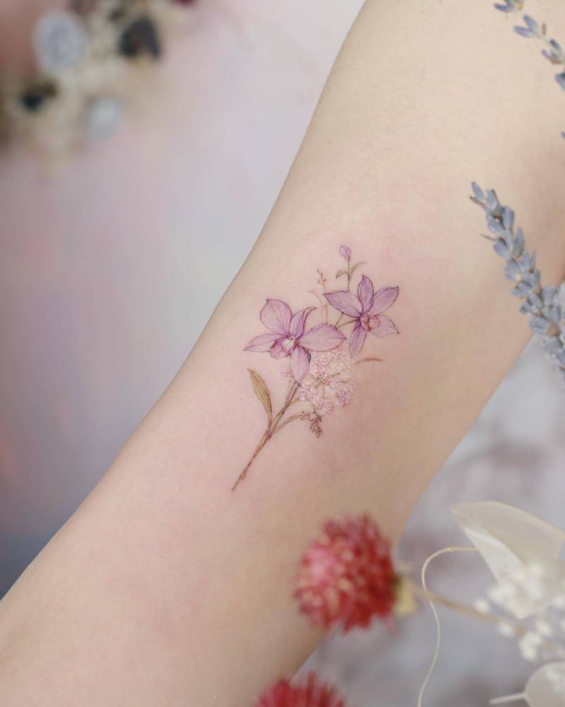 Narcissus flowers tattooed on the bicep, watercolor style.