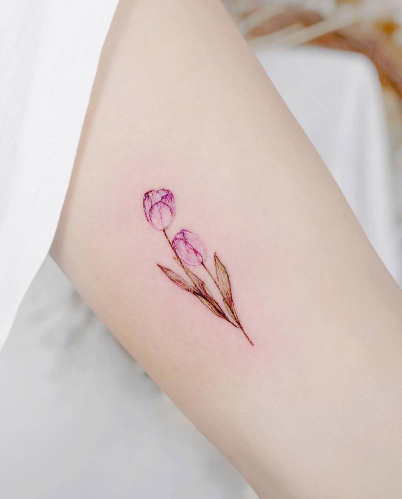 Pink tulips tattooed on the inner arm, watercolor style.