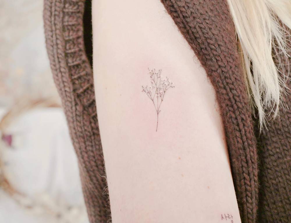 Baby's breath tattoo in fine line style placed on the upper arm.