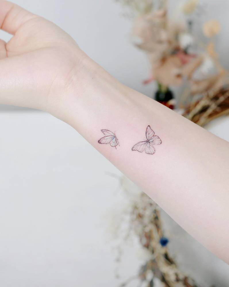 Watercolor style butterfly couple tattoo located on the wrist.