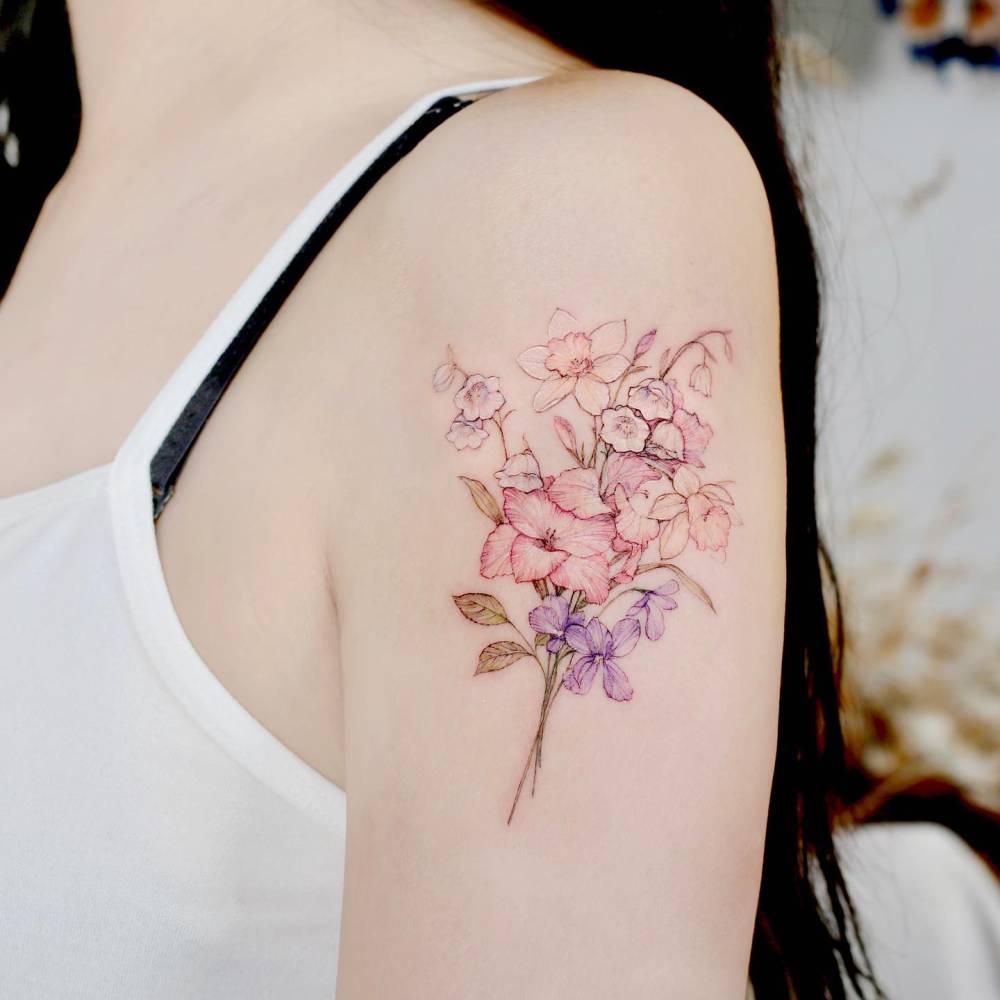 Watercolor style tattoo of a flower bouquet located on the upper arm.