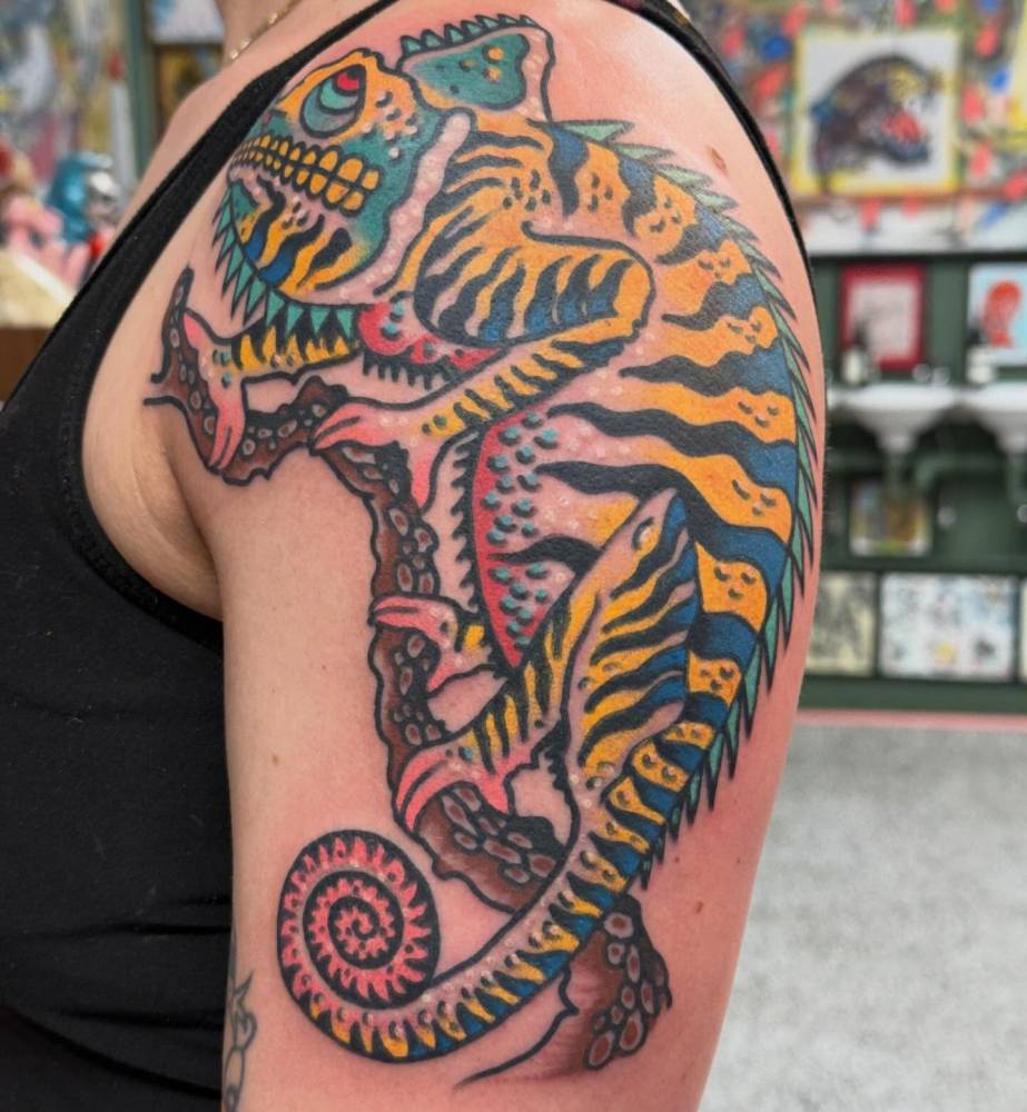 Traditional style chameleon tattoo located on the upper arm.
